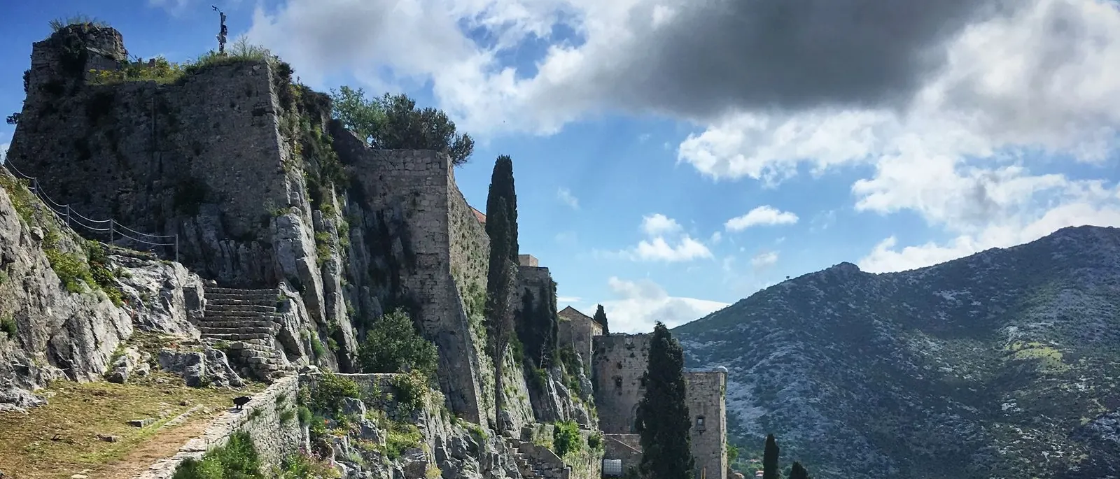 Klis Fortress on its rocky ridge above Split under a cloudy blue sky