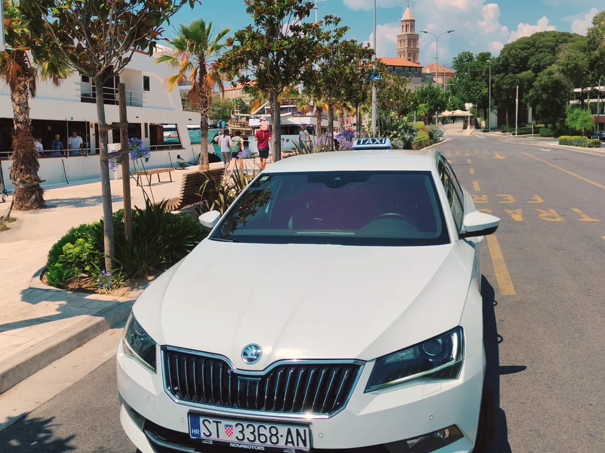 White Škoda Superb taxi on Split's waterfront with the old town bell tower in the background